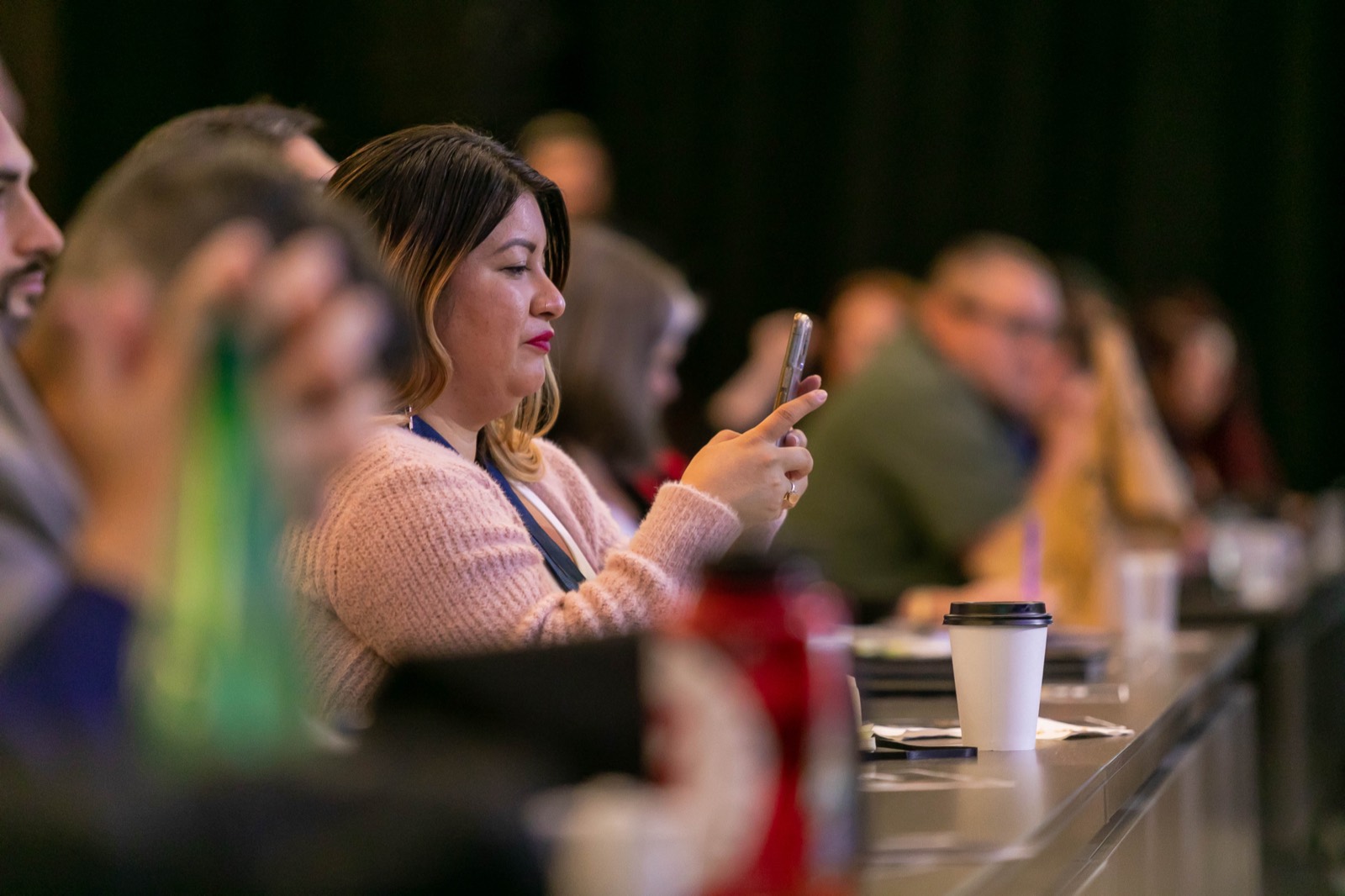 An attendee filming a session on her phone from the audience