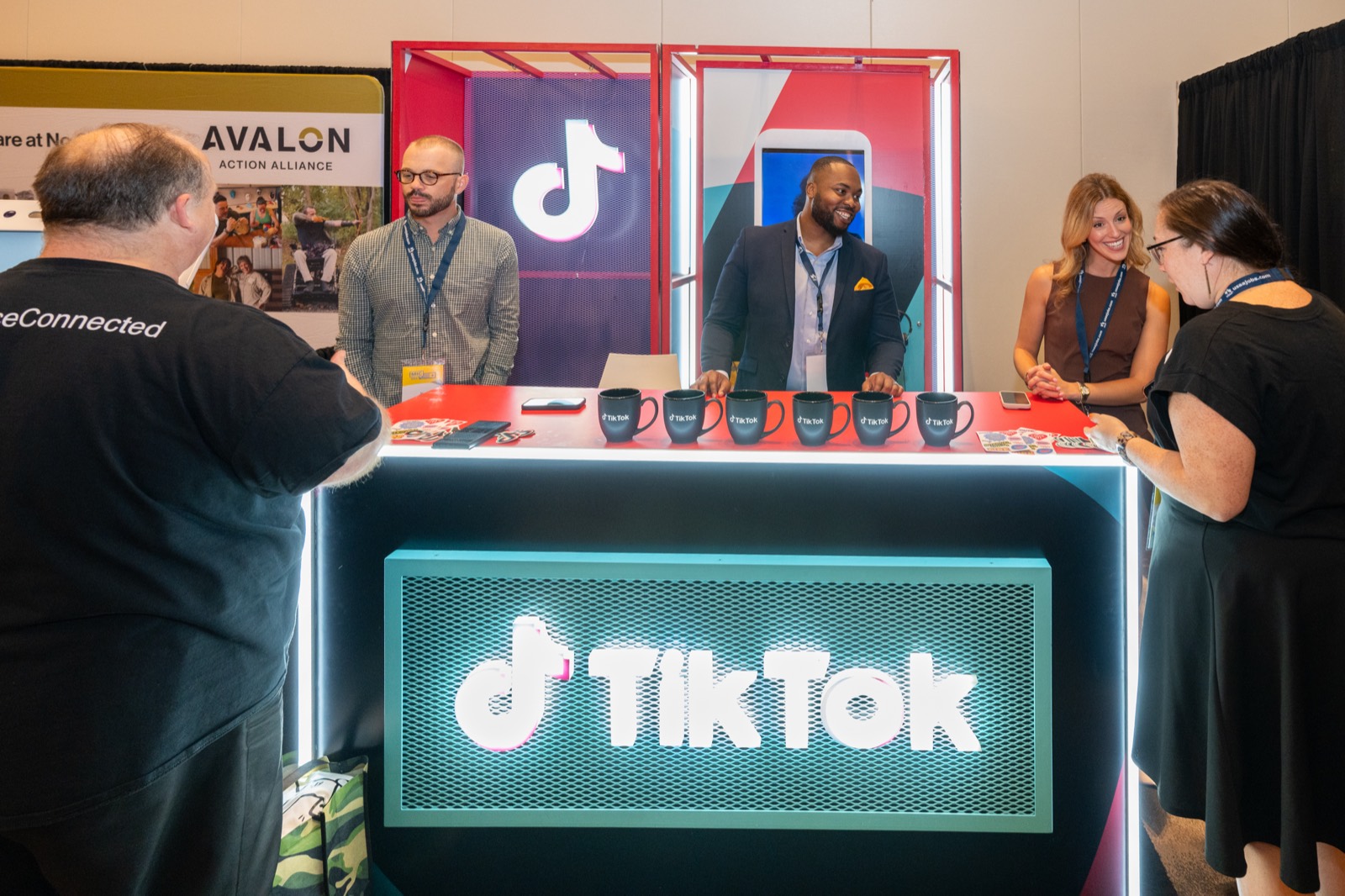 Attendees talking with platform representatives at a TikTok booth on the conference floor